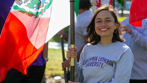 Woman smiling as she holds the Mexican flag